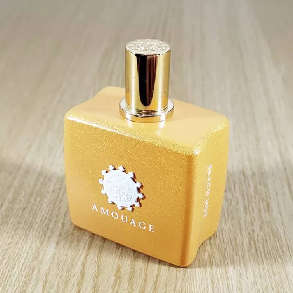Yellow square perfume bottle with a gold cap on a wooden surface.