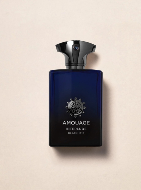 A sleek, dark blue bottle of Amouage perfume with a metallic cap on a beige surface.