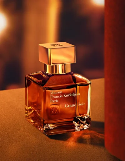 Elegant glass perfume bottle with warm amber liquid on a soft surface.