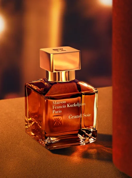 Elegant glass perfume bottle with warm amber liquid on a soft surface.